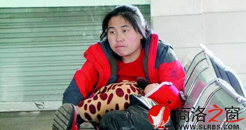 候車廳里,一位母親抱著睡著的孩子發呆